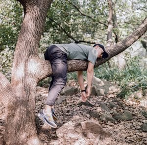 man in t-shirt and denim jeans sleeping on tree branch