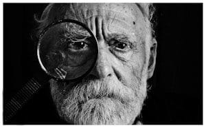 grayscale photo of man using magnifying glass