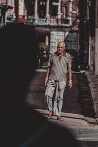 man in white and red striped shirt and gray pants standing on gray concrete pathway during
