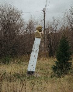 a statue of a person on a pole in a field