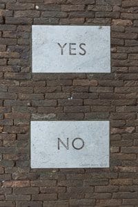 white and black yes no printed on brick wall