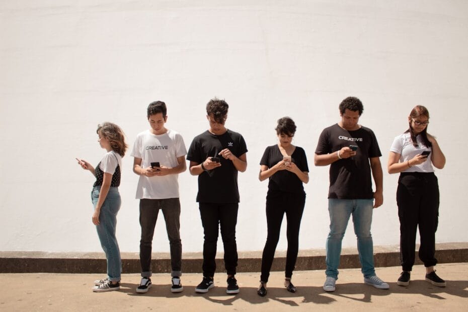group of people standing on brown floor staring at their smartphones